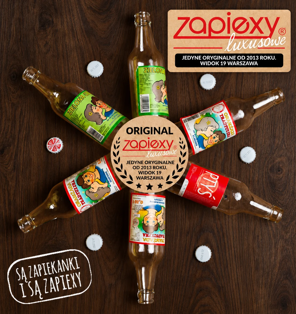 Tradycyjne oranżady na ciemnym drewnie z aktualnym logo i beżowym okrągłym znakiem Zapiexy Luxusowe